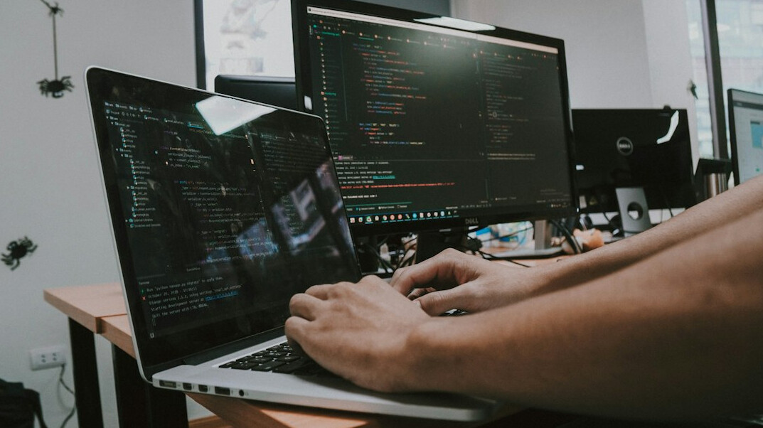 person typing code on laptop